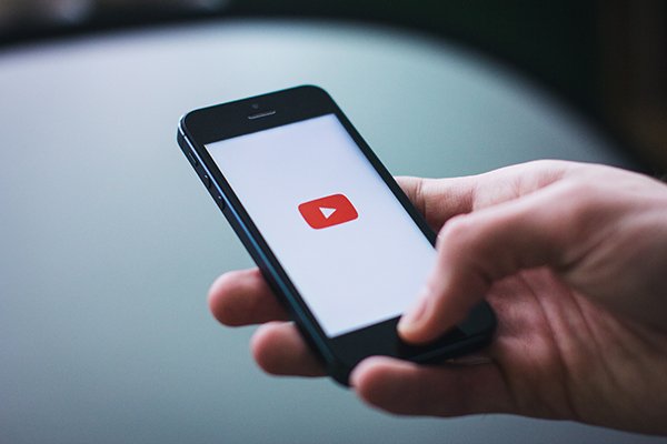 person holding smart phone with youtube logo on screen